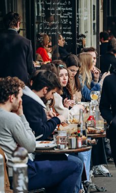 İnsanlar Montmartre, Paris 'te bir kafe terasında oturuyor.