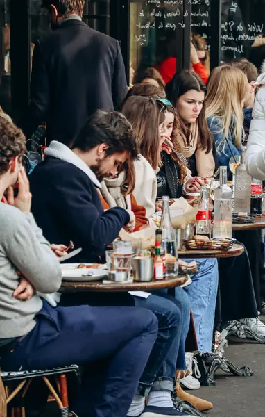 İnsanlar Montmartre, Paris 'te bir kafe terasında oturuyor.