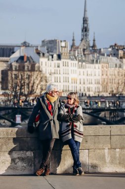 Baharda gün batımında Seine nehri üzerindeki bir köprüde duran yaşlı çift.