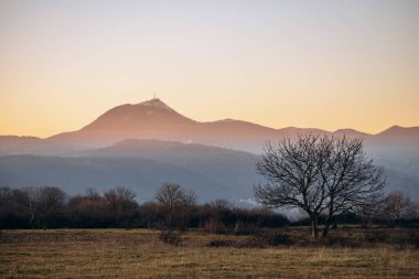 View of the famous Puy de Dome volcano from Plateau de Gergovie at winter sunset clipart