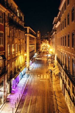 Lizbon, Portekiz - 2 Ocak 2025: Geceleri Lizbon 'da sakin bir cadde, aydınlık binalar ve kaldırımlar boyunca renkli ışıklar, canlı ama huzurlu bir atmosfer yaratıyor..