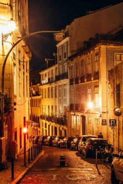 Lizbon 'daki Alfama bölgesinin resimli sokakları, sıcak ışıklarla aydınlatılıyor.