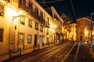 Lizbon 'daki Alfama bölgesinin resimli sokakları, sıcak ışıklarla aydınlatılıyor.