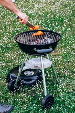 Chicken legs and merguez sausages cooking on a barbecue in the garden