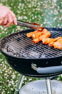 Chicken legs and merguez sausages cooking on a barbecue in the garden
