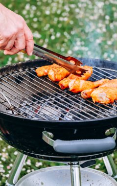 Chicken legs and merguez sausages cooking on a barbecue in the garden