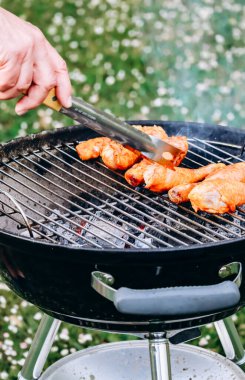 Chicken legs and merguez sausages cooking on a barbecue in the garden