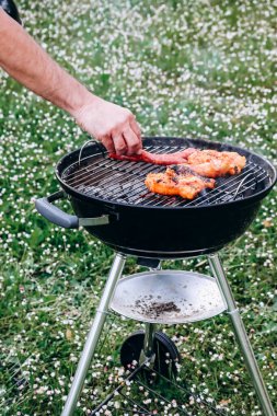 Chicken legs and merguez sausages cooking on a barbecue in the garden