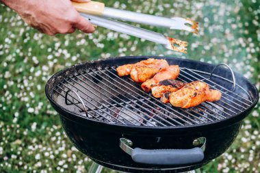 Chicken legs and merguez sausages cooking on a barbecue in the garden