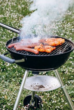 Chicken legs and merguez sausages cooking on a barbecue in the garden