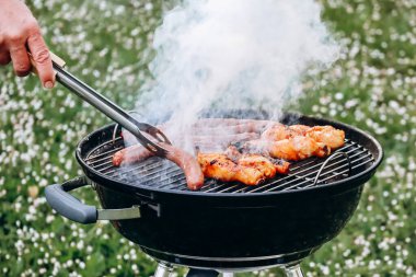 Chicken legs and merguez sausages cooking on a barbecue in the garden