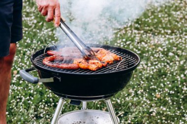 Chicken legs and merguez sausages cooking on a barbecue in the garden