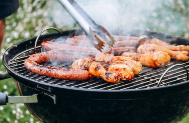 Chicken legs and merguez sausages cooking on a barbecue in the garden