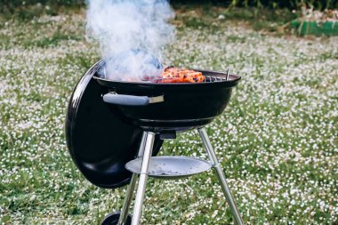 Chicken legs and merguez sausages cooking on a barbecue in the garden