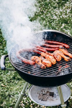 Chicken legs and merguez sausages cooking on a barbecue in the garden