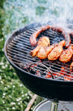 Chicken legs and merguez sausages cooking on a barbecue in the garden