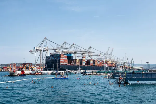 Koper, Slovenya - 16 Ağustos 2024: Adriyatik kıyısı boyunca yüzen insanlarla Koper Limanı manzarası