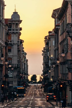Trieste, İtalya - 18 Ağustos 2024: Trieste, İtalya 'nın merkezinde, arka planda deniz bulunan pitoresk bir cadde.