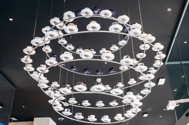 Trieste, İtalya - 18 Ağustos 2024 Trieste 'deki Illy Cafe' de asılı duran kahve fincanlarından yapılmış eşsiz bir avize.