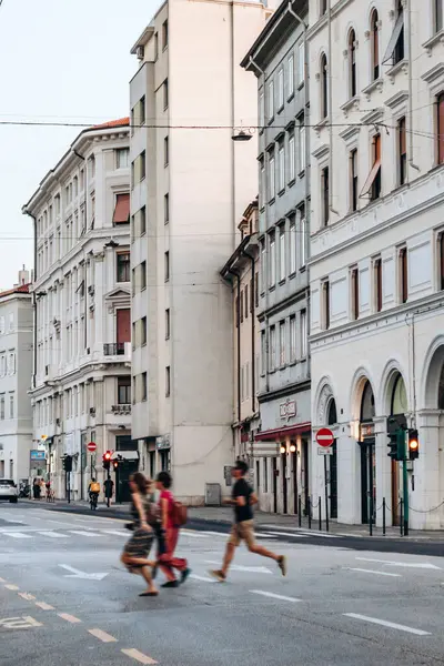 Trieste, İtalya - 18 Ağustos 2024: Trieste şehir merkezinde karşıdan karşıya geçen üç kişi, arka planda kentsel trafik