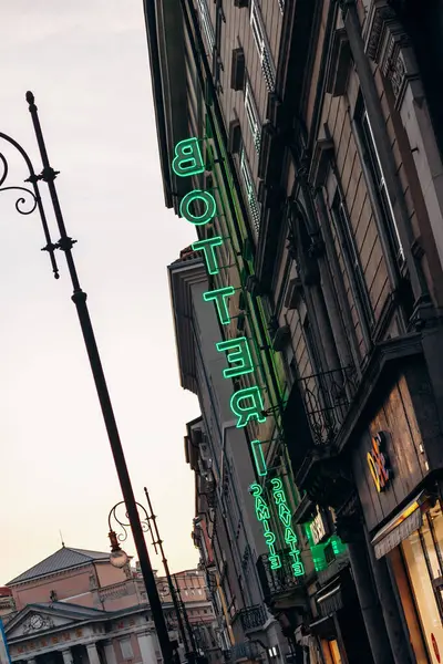 Trieste, İtalya - 18 Ağustos 2024: Aydınlatılmış neon tabela, binanın ön cephesinde Trieste 'nin kalbinde canlı bir parıltı bıraktı.