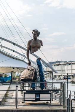 Cenova, İtalya - 22 Eylül 2024: Bruno Catalano 'nun bronz heykeli, Porto Antico' da yolculuğu ve kimliği sembolize eden çantalı bir gezgini resmediyor..