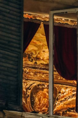 Açık pencereden gece görüşü, Via di Scurreria 'daki tarihi binada süslü freskli tavan ve kırmızı perdeleri gösteriyor..