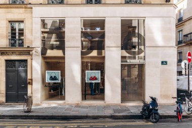 Paris, Fransa - 23 Şubat 2025: Saint-Honore sokağındaki Acne Stüdyoları butik ön cephe, büyük cam pencereli minimalist taş dış cephe, vitrinde el çantaları, park edilmiş scooter ve bisikletler