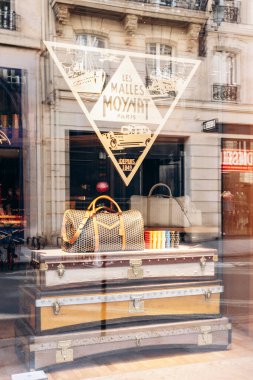 Paris, Fransa - 23 Şubat 2025: Saint-Honore sokağındaki Moynat butik vitrini, imzalı monogram ve renkli deri aksesuarlı lüks seyahat çantası