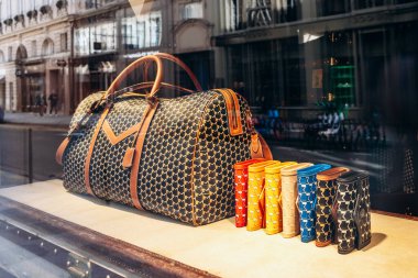 Paris, Fransa - 23 Şubat 2025: Saint-Honore sokağındaki Moynat butik vitrini, imzalı monogram ve renkli deri aksesuarlı lüks seyahat çantası