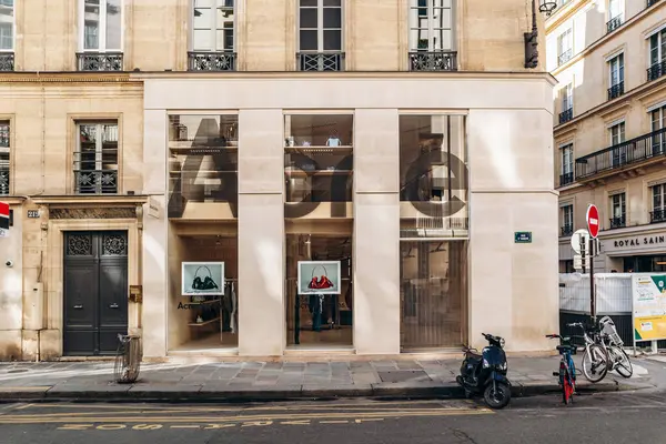 Paris, Fransa - 23 Şubat 2025: Saint-Honore sokağındaki Acne Stüdyoları butik ön cephe, büyük cam pencereli minimalist taş dış cephe, vitrinde el çantaları, park edilmiş scooter ve bisikletler