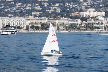 Cannes, Fransa - 8 Mart 2025: Sakin denizde yelkenli ve arka planda tepeler.