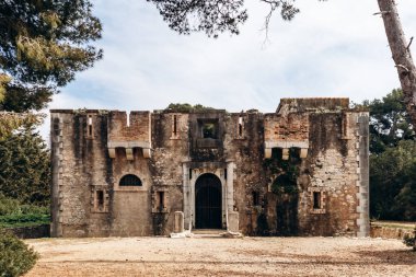 Sainte-Marguerite Adası 'ndaki Fort Royal' in tarihi taş binası çam ağaçlarıyla çevrili..