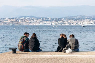 Cannes, Fransa - 8 Mart 2025 Sainte-Marguerite Adası 'nda Cannes şehri manzaralı bir grup arkadaş.