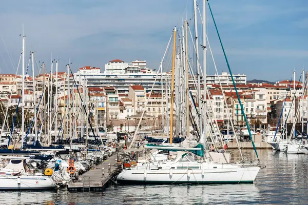 Cannes, Fransa - 8 Mart 2025: Arka planda Palais des Festivals ve şehir tepeleriyle Eski Liman 'da balıkçı tekneleri ve yatlar.