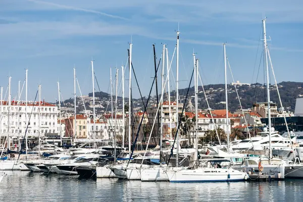 Cannes, Fransa - 8 Mart 2025: Arka planda Palais des Festivals ve şehir tepeleriyle Eski Liman 'da balıkçı tekneleri ve yatlar.