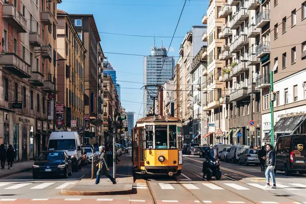 Milan, İtalya - 19 Mart 2025: Tarihi binaları ve modern gökdeleniyle Milano şehir merkezinde klasik sarı tramvay
