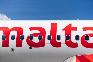 Malta Uluslararası Havalimanı - 9 Nisan 2025: Açık gökyüzü altında kırmızı logo harfleri ve yolcu pencereleriyle Air Malta uçak gövdesinin kapatılması
