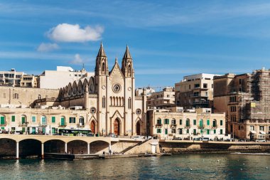 Balluta Körfezi, Malta - 9 Nisan 2025: Neo-gotik Karmelit Kilisesi, geleneksel ve modern binalarla çevrili olan St Julian 's ve Sliema arasındaki Balluta Körfezi' nin rıhtımında yer almaktadır.