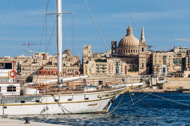 Sliema, Malta - 9 Nisan 2025: Sliema limanından Valletta 'nın panoramik manzarası yelkenli yatı, kireçtaşı binaları ve Carmel Dağı' nın Leydisi Bazilikası 'nın ikonik kubbesi