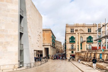 Valletta, Malta - 10 Nisan 2025: Neoklasik kireç taşı binası, yeşil Malta balkonları, antik sütunlar ve işlek yaya sokağı, canlı şehir atmosferi