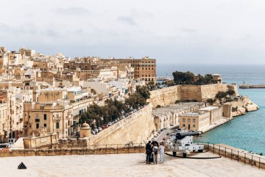 Valletta, Malta - 10 Nisan 2025: Tarihi kireçtaşı tahkimatları, şehir çatıları ve turkuaz Akdeniz manzaralı kıyı şeridi panoramik görünümü
