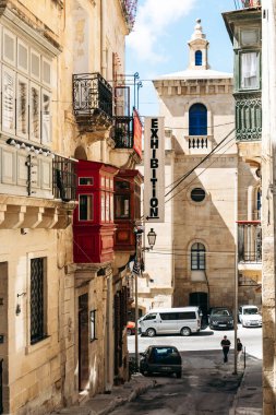 Birgu, Malta - 11 Nisan 2025: Geleneksel Malta balkonları kırmızı ve yeşil, demir parmaklıklar, sergi işareti ve kireç taşı mimarisi ile antik taş caddeler