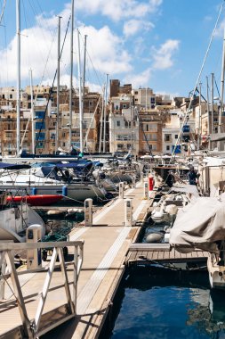 Senglea, Malta - 10 Nisan 2025: Geleneksel Malta liman binalarının manzarası ve Senglea ile Birgu arasında renkli balkonlar, güneşli bir baharda limanda demirlemiş tekne ve yatlar