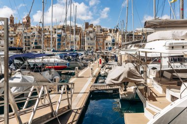 Senglea, Malta - 10 Nisan 2025: Geleneksel Malta liman binalarının manzarası ve Senglea ile Birgu arasında renkli balkonlar, güneşli bir baharda limanda demirlemiş tekne ve yatlar