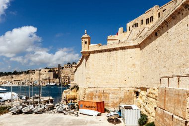 Birgu, Malta - 11 Nisan 2024: Birgu 'daki St. Angelo Kalesi' nin tarihi kale duvarları ve gözlem kulesi, Grand Harbour 'a bakan küçük yelkenli tekneleri aşağıda demirli.