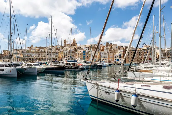 Senglea, Malta - 10 Nisan 2025: Geleneksel Malta liman binalarının manzarası ve Senglea ile Birgu arasında renkli balkonlar, güneşli bir baharda limanda demirlemiş tekne ve yatlar