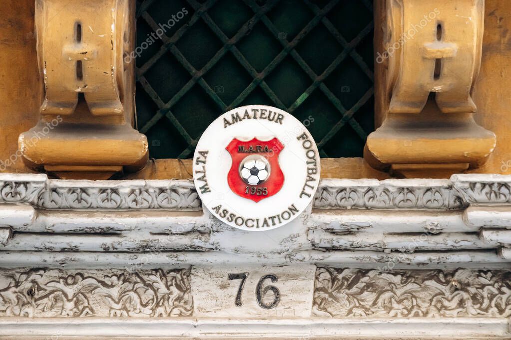 Valletta, Malta - April 9, 2025: Malta Amateur Football Association plaque with red shield and soccer ball above an ornate doorway at number 76 in the city center
