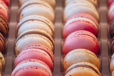 Assorted colorful macarons arranged in rows at a French patisserie