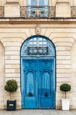 Paris, France - September 7, 2025: Ornate blue door on Place Vendome with classic architecture and potted trees